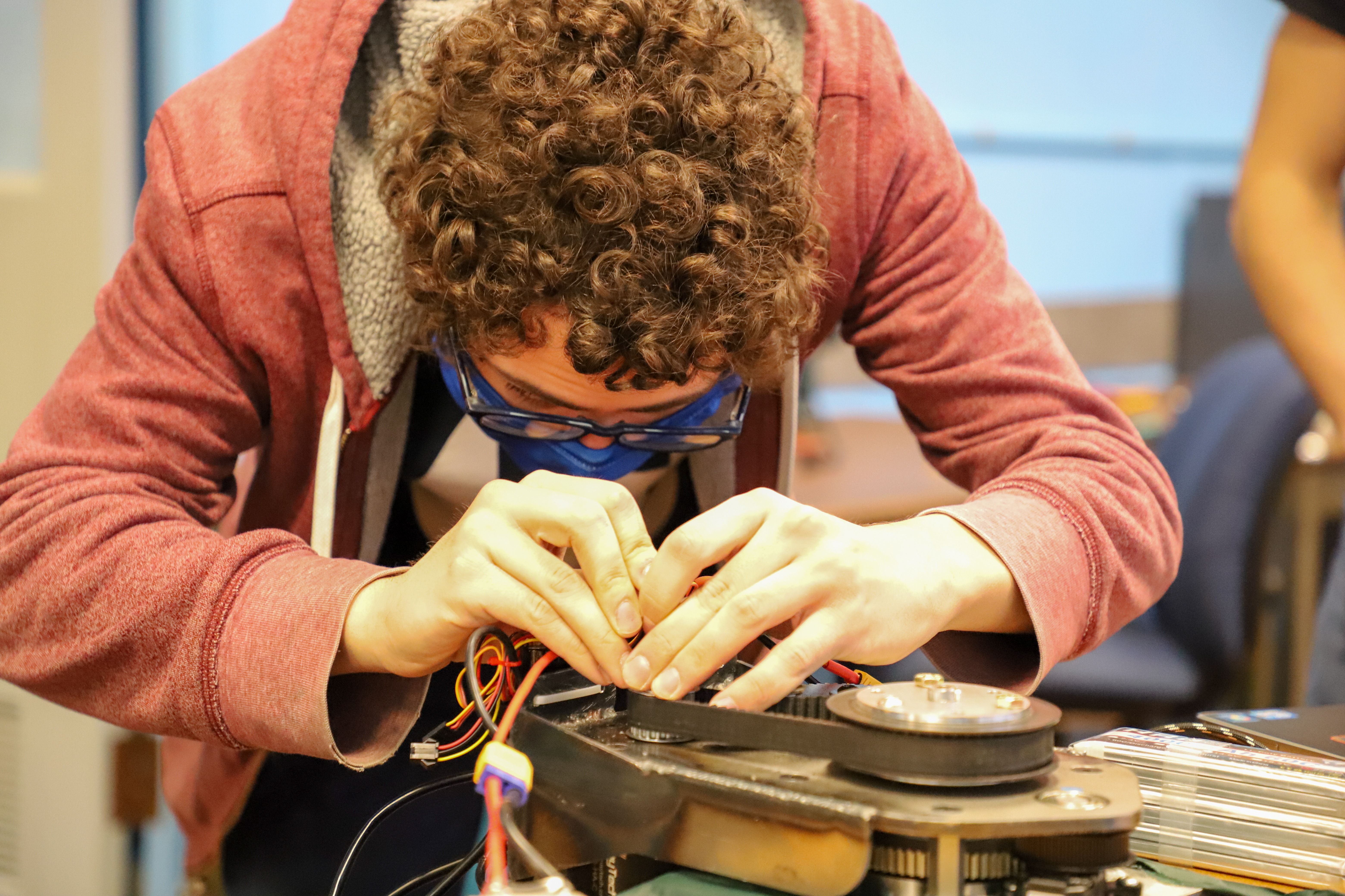 A ϲʷ¼ student works on the wiring of the robot's wheel.