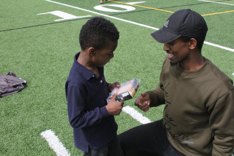 A ϲʷ¼ student gives a toy to a child during Spring Fest.