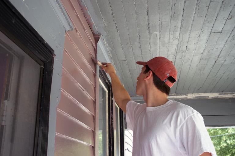 Student painting a house in Flint as part of Service Saturday activities at ϲʷ¼.